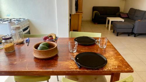 a table with plates and a bowl of fruit on it at נווה במדבר - שופץ ב-2025! צמוד ל BGU וסורוקה - אינטרנט סיבים, Google TV ומיזוג מלא in Beer Sheva