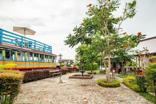 a bus parked next to a tree next to a building at La Trasnochadora - Duerme en una típica finca cafetera Colombiana in Pereira
