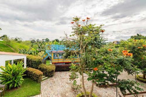 a garden with a colorful bus and a tree at La Trasnochadora - Duerme en una típica finca cafetera Colombiana in Pereira