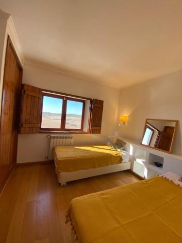 a bedroom with two beds and a window at Montadinho Houses in São Bartolomeu da Serra