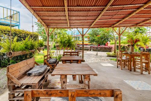an outdoor patio with wooden benches and tables at La Trasnochadora - Duerme en una típica finca cafetera Colombiana in Pereira