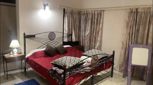 a bedroom with a bed with red sheets and pillows at Taj Waves Villa - Pink Barbie Themed Pool View Room in Agra