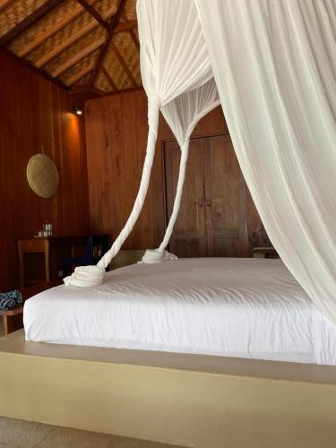 a bedroom with a bed with white curtains at Tumbuh Oasis in Letman