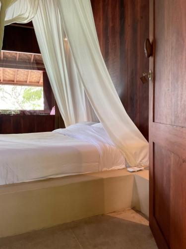 a bedroom with a bed with a curtain over a window at Tumbuh Oasis in Letman