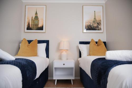 two twin beds in a room with pictures on the wall at Cosy Luxe 3Bed Retreat Hot Tub BBQ Parking Near Town Perfect for Contractors Families Short & Long Stay in Hythe