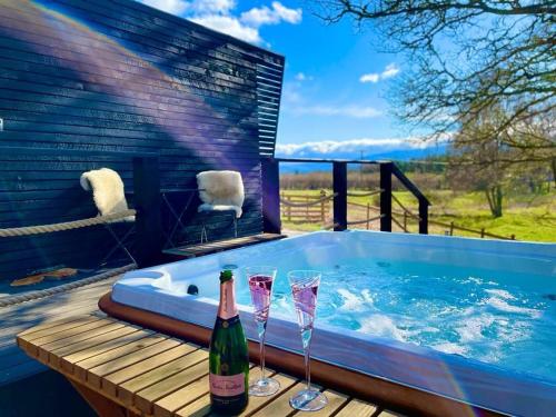 a hot tub with two glasses and a bottle of champagne at Dog friendly cabin & hot tub and Cairngorm views in Aviemore
