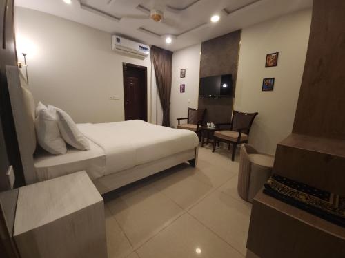 a hotel room with a bed and a table and chairs at Aspire Lodge, G11 Islamabad - A Family Guest House & Hotel in Islamabad