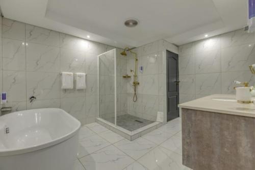 a bathroom with a shower and a tub and a sink at Summit Della Suite in Centurion