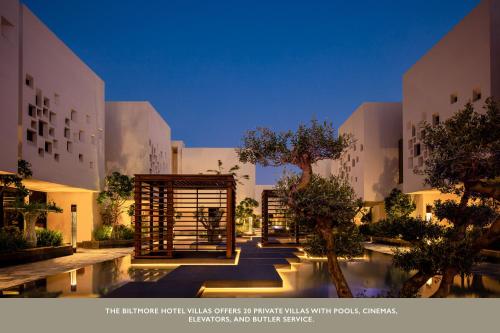 a building with a courtyard with trees and a pool at The Biltmore Hotel Villas, Dubai in Dubai