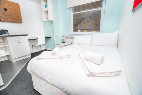 a bedroom with a white bed with towels on it at Lovely Modern Central Coventry Budget Studio in Coventry