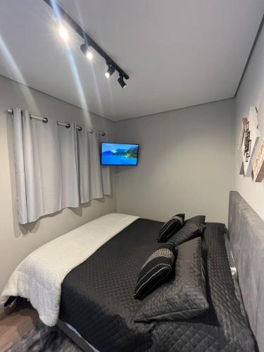 a bedroom with a bed and a flat screen tv at São Roque Chalés in São Roque