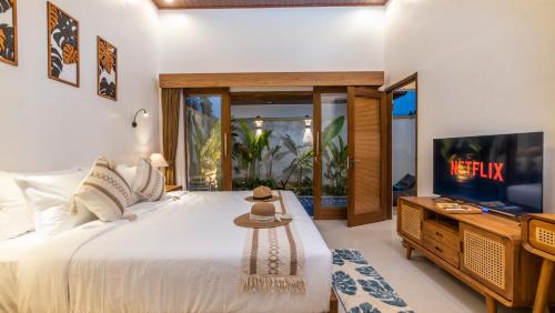 a bedroom with a large bed and a tv at Taman Kencana Ubud in Ubud