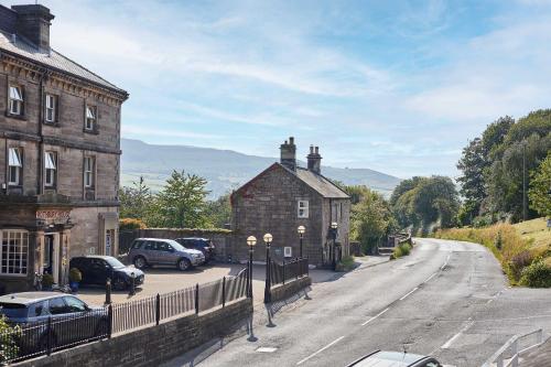 a street with cars parked next to a building at Host & Stay - Brackenrigg Cottage in Rothbury
