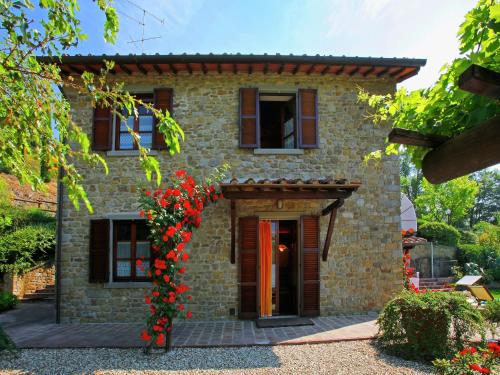 una casa de piedra con flores rojas delante de ella en Villa in Tuscany with Pool and Valley Views, en Castiglion Fiorentino
