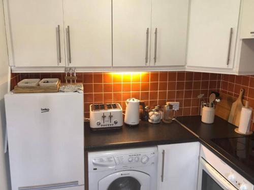 a kitchen with white cabinets and a washer and dryer at Bayview Villa Costal Retreat in Youghal