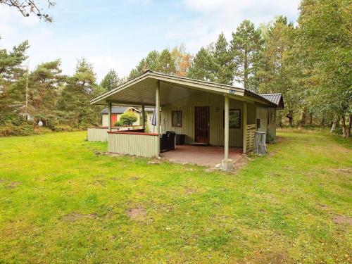 a small house with a porch in a field at 6 person holiday home in Rødby in Rødby