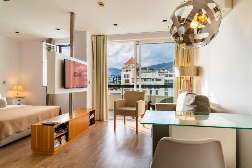a hotel room with a bed and a desk and a window at Golden escape in Funchal in Funchal
