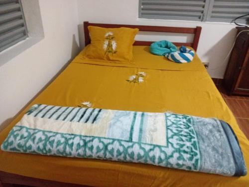 two beds in a room with a yellow bedsheet at Chez Pauline in Sainte Marie