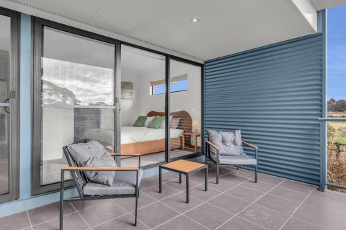 a bedroom with a bed and two chairs and a table at Saltwater Apartments in Eden