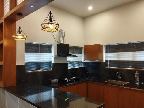 a kitchen with a black counter top and some windows at Highrange Retreat in Idukki