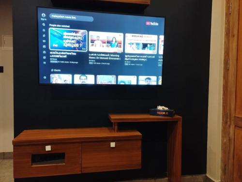 a flat screen tv on a wall with a wooden table at Highrange Retreat in Idukki