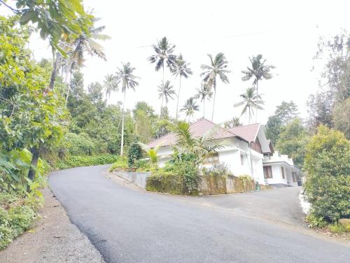 a house on the side of a road with palm trees at Highrange Retreat in Idukki