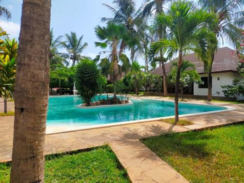 Una piscina con palmeras en un patio. en Kobe House, en Malindi