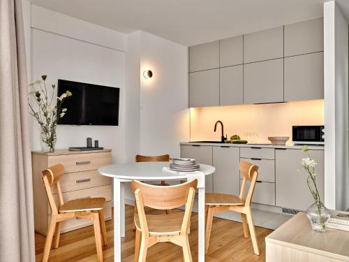 a kitchen and dining room with a white table and chairs at Apartamenty Media Park in Warsaw