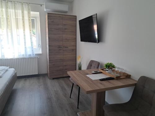 a living room with a wooden table and a bedroom at Vár-Völgye Vendégház in Csesznek
