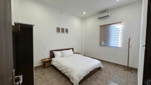 a white bedroom with a bed and a window at D'Igel Boutique in Da Nang