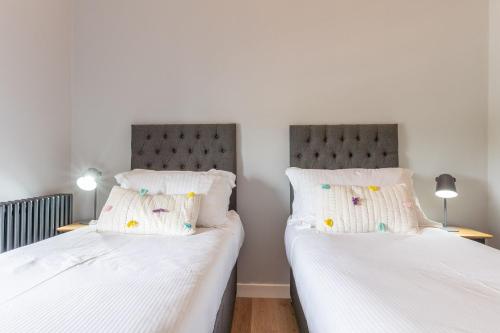 two twin beds in a bedroom with white sheets at The Stables in Holyhead