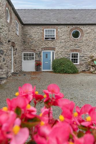 a stone house with pink flowers in front of it at The Stables in Holyhead