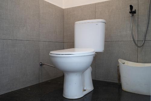 a white toilet in a bathroom with a shower at Kuleum Camp And Cabin By ARBA in Baruhtunggul