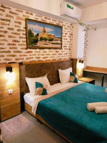 a bedroom with a large bed with a painting on the wall at Hotel Hirot Inn in Tashkent