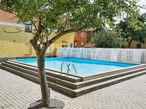 a swimming pool with a tree in front of a building at 4 person holiday home in Gudhjem-By Traum in Gudhjem