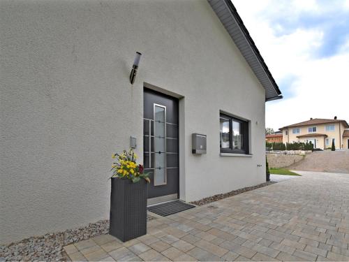 a house with a black door with a vase of flowers at Bodenwöhr Lakeside Gem in Bodenwöhr