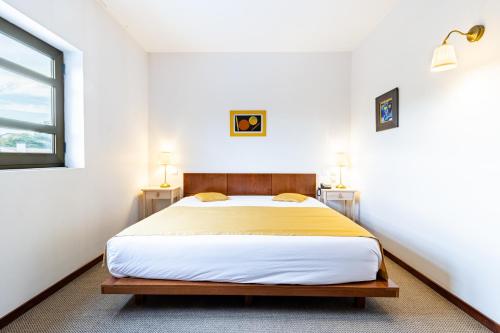 a bedroom with a bed with white walls and a window at Hotel La Fontaine in Esmoriz