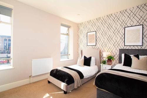 a bedroom with two beds and two windows at Boutique Central 2 bed In Harrogate - Sleeps 6 in Harrogate