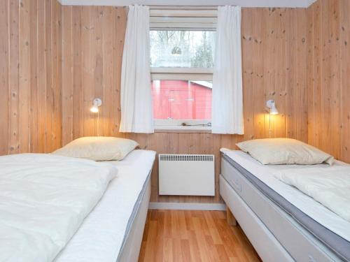 two beds in a room with wooden walls and a window at 10 person holiday home in Glesborg-By Traum in Fjellerup Strand
