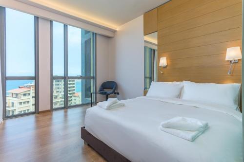 a bedroom with a large white bed and a large window at Jounieh Living - Residences by Local Host in Ed Dkârîne