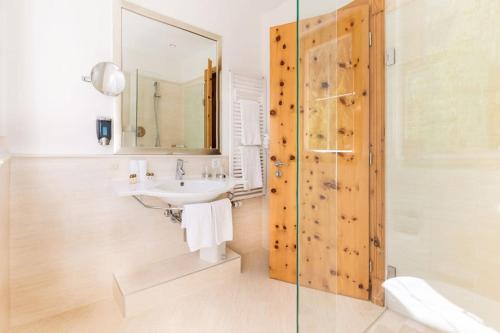 a bathroom with a sink and a shower with a mirror at Chasa Castello relax & spa in Samnaun