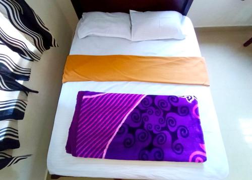 a bed with an orange and purple blanket on it at Misty valley Private Pool Villa Munnar in Anachal