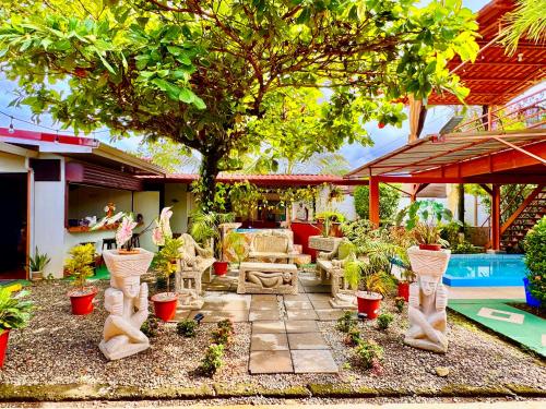 a garden with a patio with a tree and a pool at Villas Ela en Bahía Ballena,Uvita Hermosas habitaciones privadas grandes, piscina, cocina, jacuzzi, aire acondicionado, tv y baño privado in Uvita