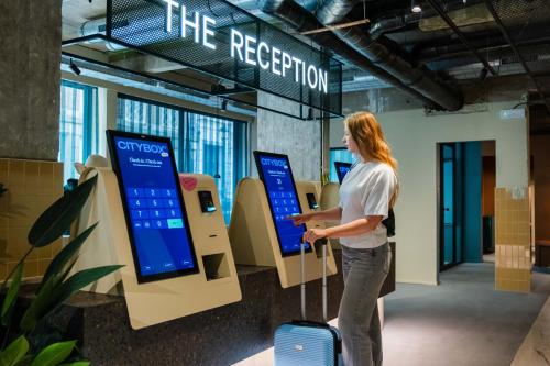 a woman standing in an airport with her luggage at Citybox Brussels in Brussels