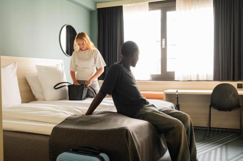 a woman talking to a man sitting on a bed at Citybox Brussels in Brussels