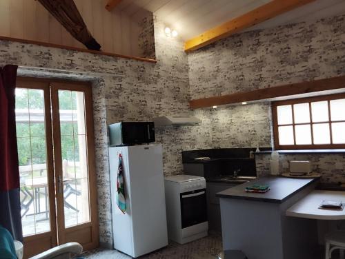 a kitchen with a white refrigerator in a room at LA FORGE DU LUCIMOND in Saint-André