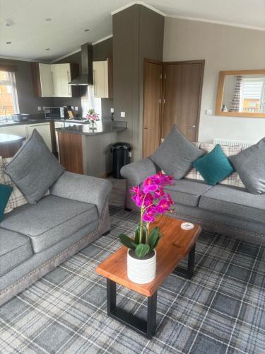 a living room with a couch and a table with flowers at Hepburns Lodge 19 in Strachan