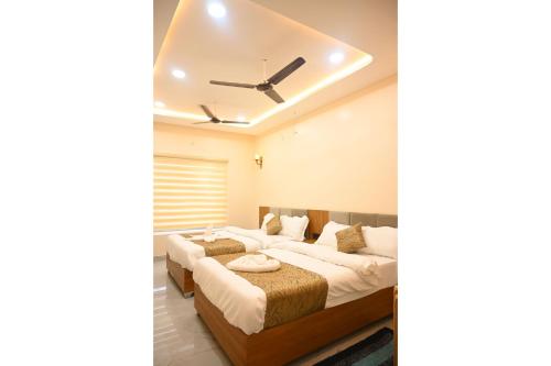 a bedroom with two beds and a ceiling fan at Aryavart Hotel in Ayodhya