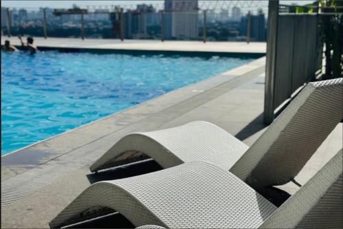 a swimming pool with two lounge chairs next to it at Cozy Staycation with Netflix, Pool, PS4, Board Games in Manila