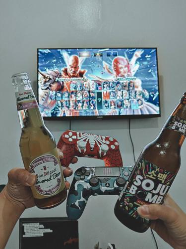 two people holding bottles of beer and a video game controller at Cozy Staycation with Netflix, Pool, PS4, Board Games in Manila